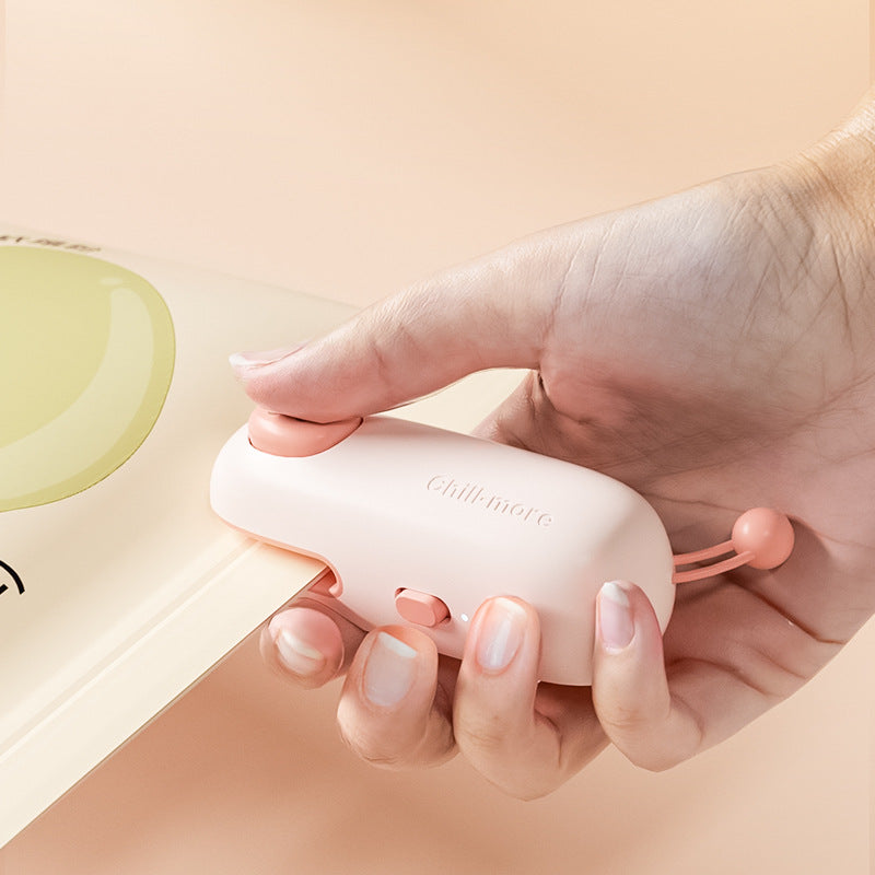Hand holding the compact Pink Pig rechargeable snack bag sealer